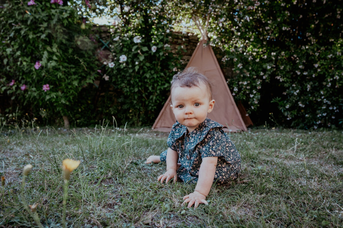 petite fille à genou dans jardin herbe verte tipi
