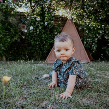 petite fille à genou dans jardin herbe verte tipi
