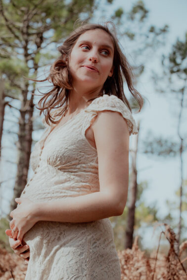 femme enceinte ventre rond robe blanche cheveux au vent pins nature