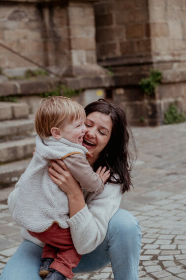 fils dans bras maman accroupie pavés rue
