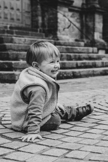 petit garçon assis sur pavés sourire