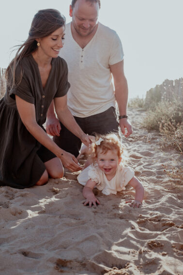parents avec petite fille dans le sable plage