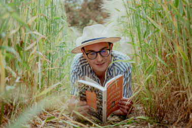 lecture livre touristique auteur chapeau de paille allongé champs