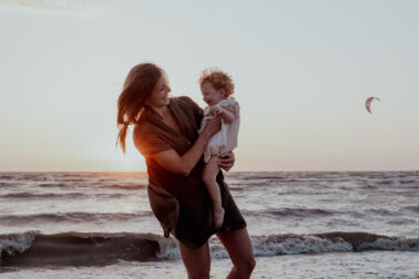 mère fille dans bras bord de l'eau plage mer coucher de soleil
