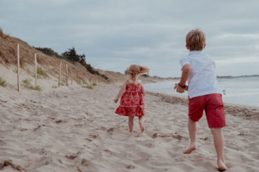 frère et sœur courir sable de dos