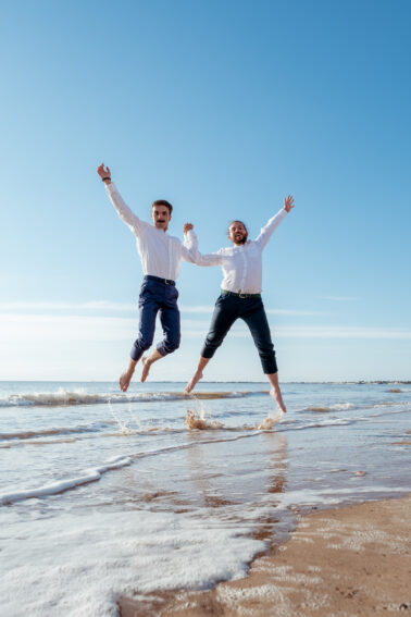 deux jeunes hommes saut plage mer costume mariage