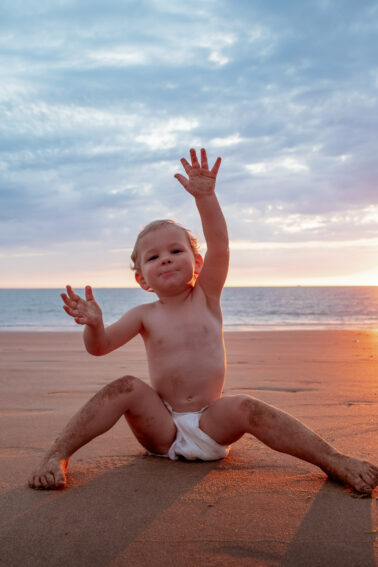 bébé assis sable mouillé couche-culotte mer coucher de soleil