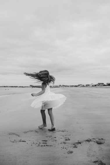 petite fille danse robe virevoltant sable mouillé plage